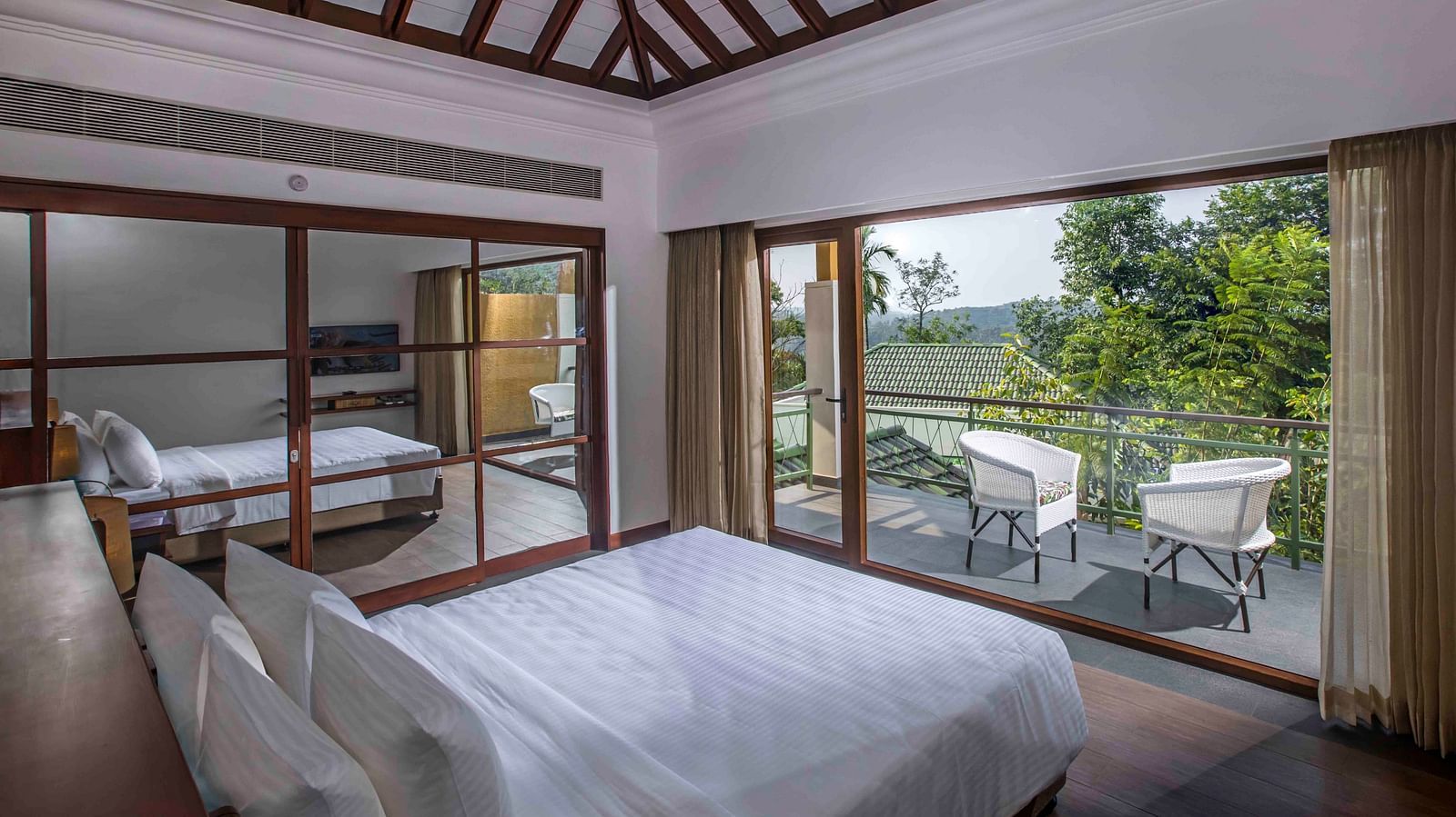 Image of the bed at the villa of our hotel with expansive glass window | Great Trails Wayanad by  GRT hotels.