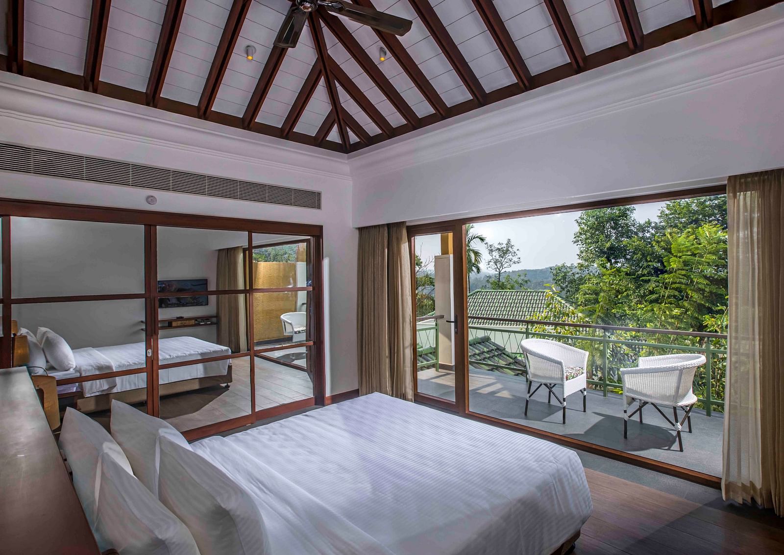 Image of the bed at the villa of our hotel with expansive glass window | Great Trails Wayanad by  GRT hotels.