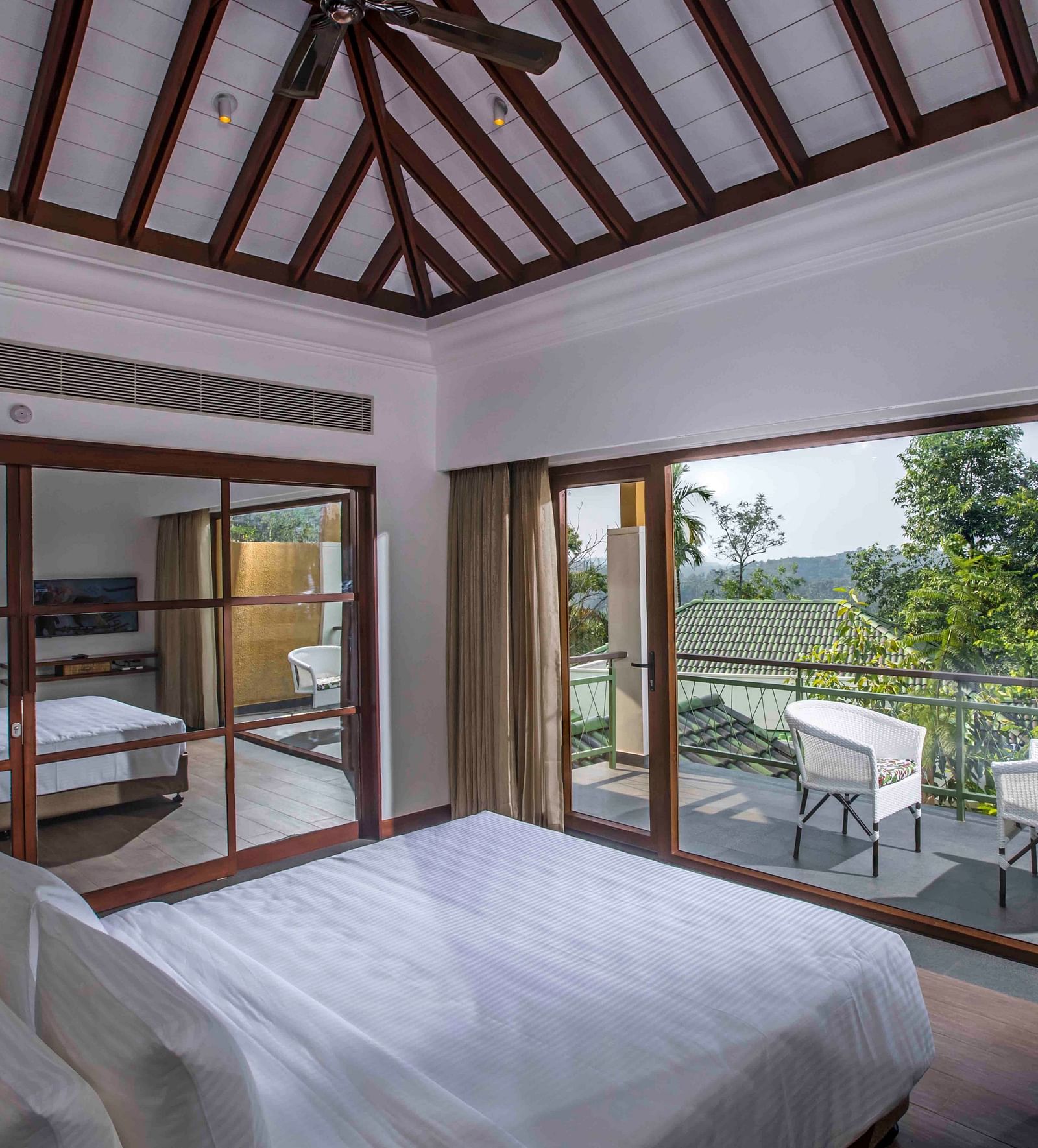 Image of the bed at the villa of our hotel with expansive glass window | Great Trails Wayanad by  GRT hotels.
