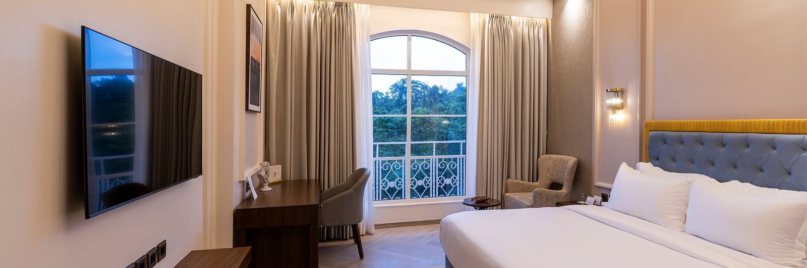 The Deluxe Room featuring a neatly kept double bed with a flat screen television in front of it at Imperial Goa.