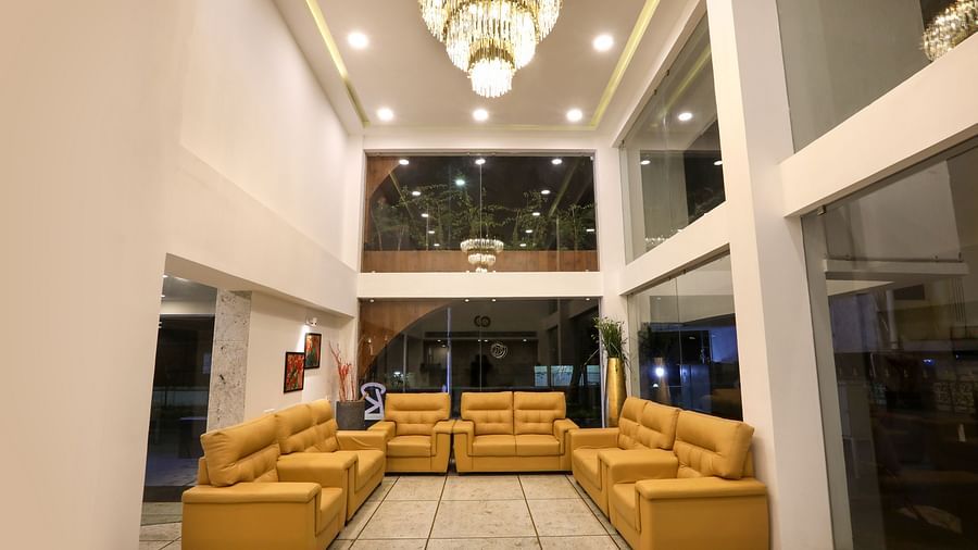 The lobby of a hotel with a large chandelier and sofas kept in a cluster - Mango Hill Central, Chennai