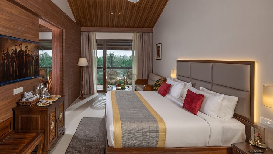 A large bedroom of Raja Ravi Varma Suite with a king size bed and a wooden headboard at Uday Suites