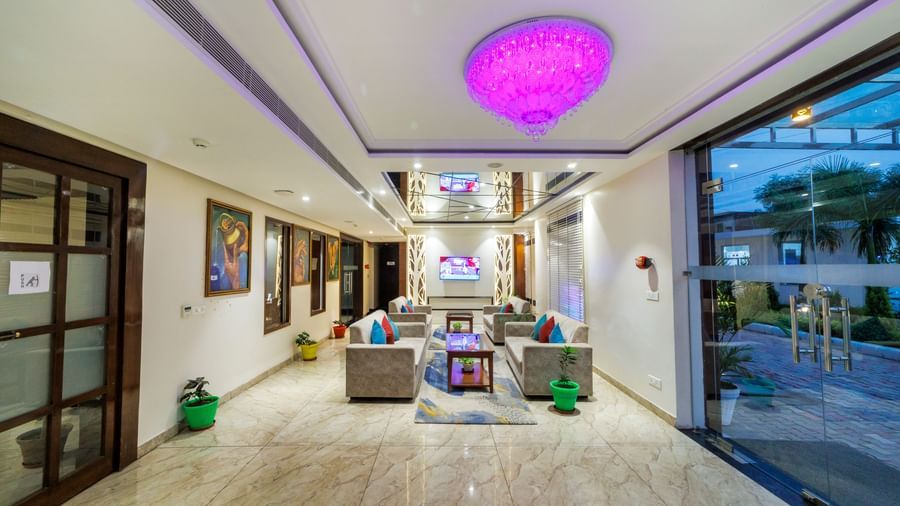 Entrance of Inde Reva Resorts Rishhikesh with chandelier lighting, artwork, and glass doors.