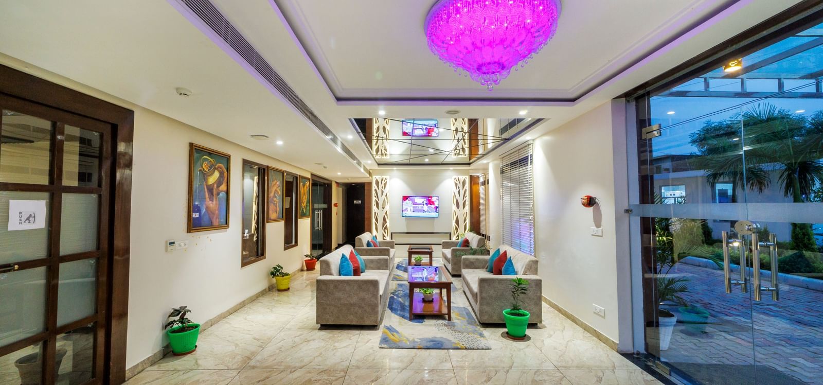 Entrance of Inde Reva Resorts Rishhikesh with chandelier lighting, artwork, and glass doors.