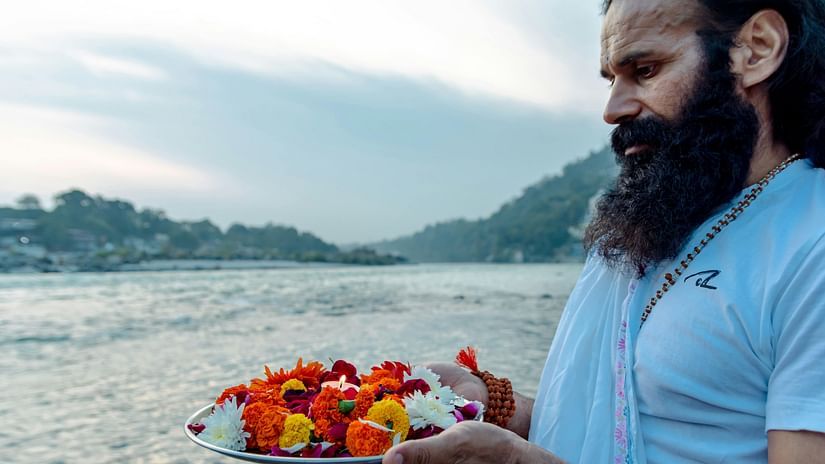 A person offering flowers to the holy waters at Triveni Sangam