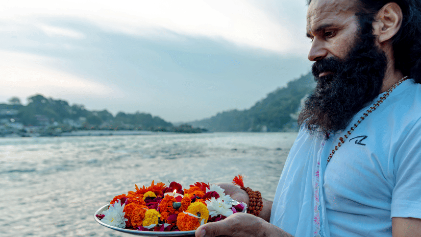 A person offering flowers to the holy waters at Triveni Sangam
