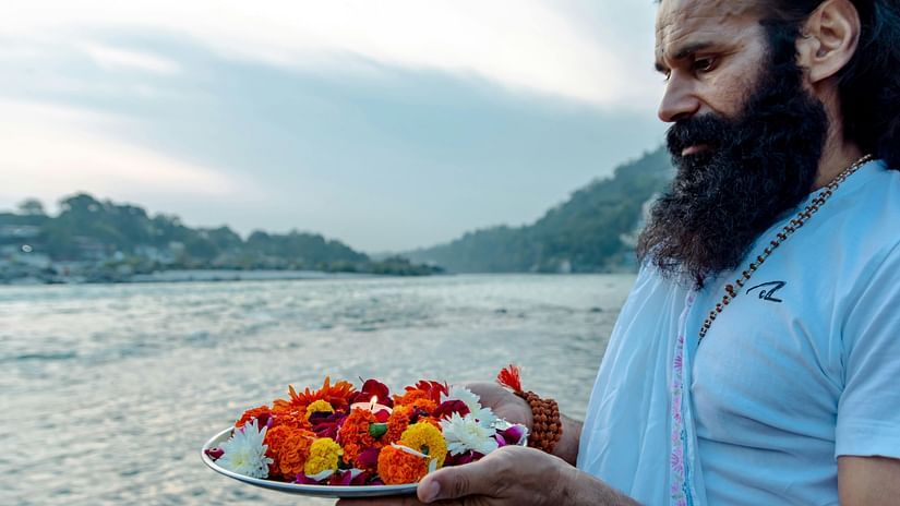 A person offering flowers to the holy waters at Triveni Sangam