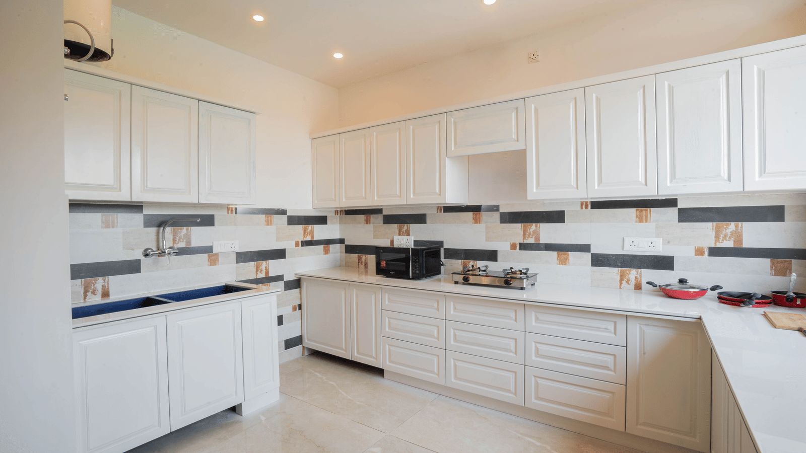 A kitchen with cabinets, tiled walls, and cooking appliances at Perfectstayz Value Paradise, Mussoorie.