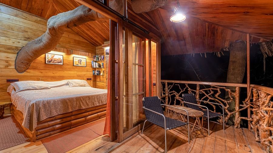 Cosy wooden room with a bed and a decorative railing of the balcony - BluSalzz Collection - Tranquil Resort, Wayanad