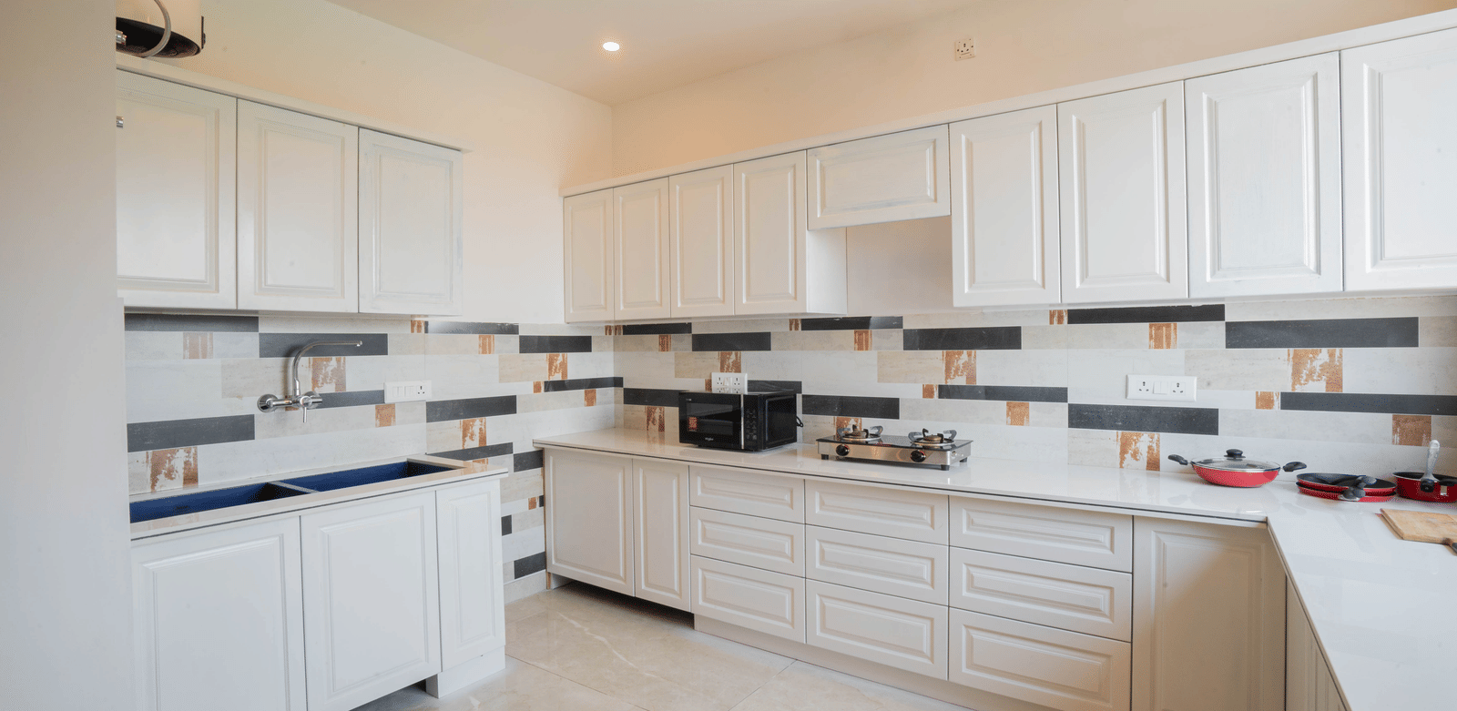 A kitchen with cabinets, tiled walls, and cooking appliances at Perfectstayz Value Paradise, Mussoorie.