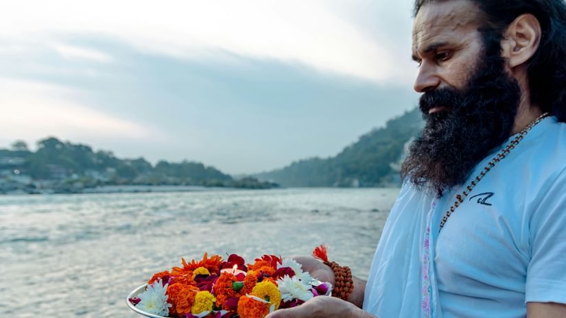 A person offering flowers to the holy waters at Triveni Sangam