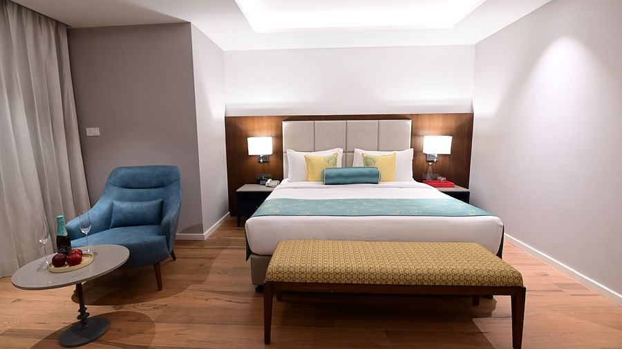 Deluxe Room at Golden Tulip, Goa Vagator with a double bed, a sofa chair and a coffee table