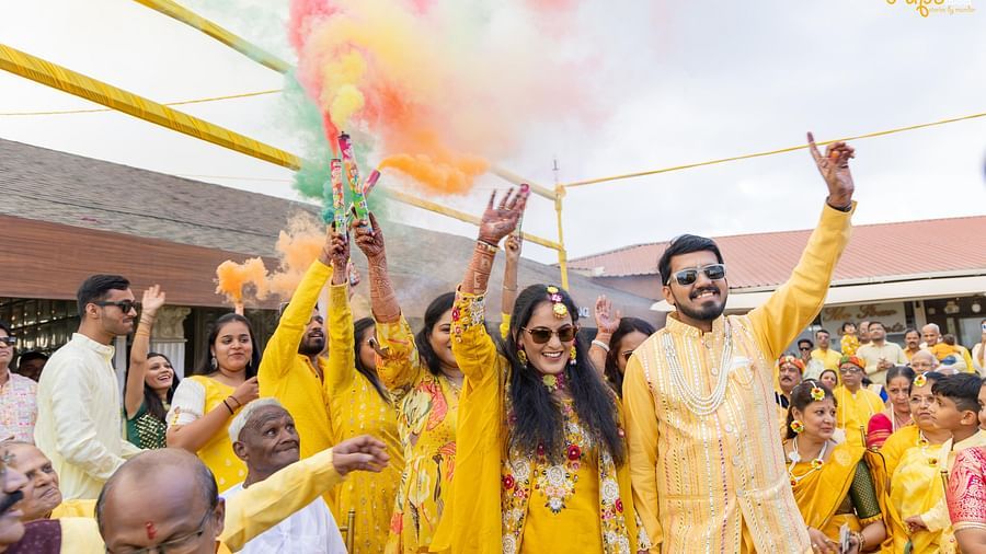 A jubilant wedding party throws colorful powder into the air, celebrating under a tent with and fabric, expressing happiness - The Grand Legacy Resort and Spa