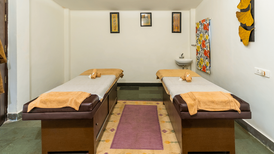 Two massage tables neatly prepared with folded towels in a brightly lit spa room | Anandam Jungle Retreat Resort, Udaipur