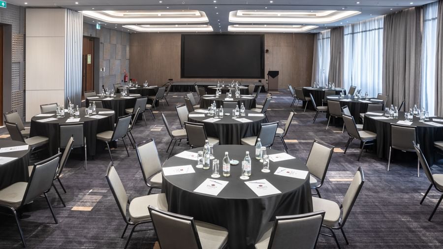 Spacious banquet hall at Best Western Premier Westlands hotel, set up with round tables for an event, featuring plush carpeting and ceiling lights.
