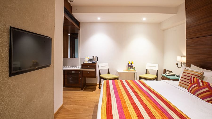 An executive room illuminated by dim lights, featuring a flat-screen TV and a comfy bed, creating a cozy and relaxing atmosphere