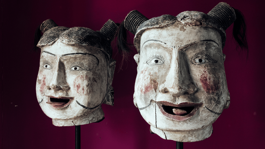 A pair of traditional decorative masks displayed against a backdrop at Owl and the Pussycat Hotel in Galle.