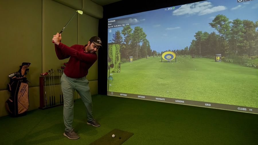 image of a man playing golf in golf simulator at The Claridges New Delhi
