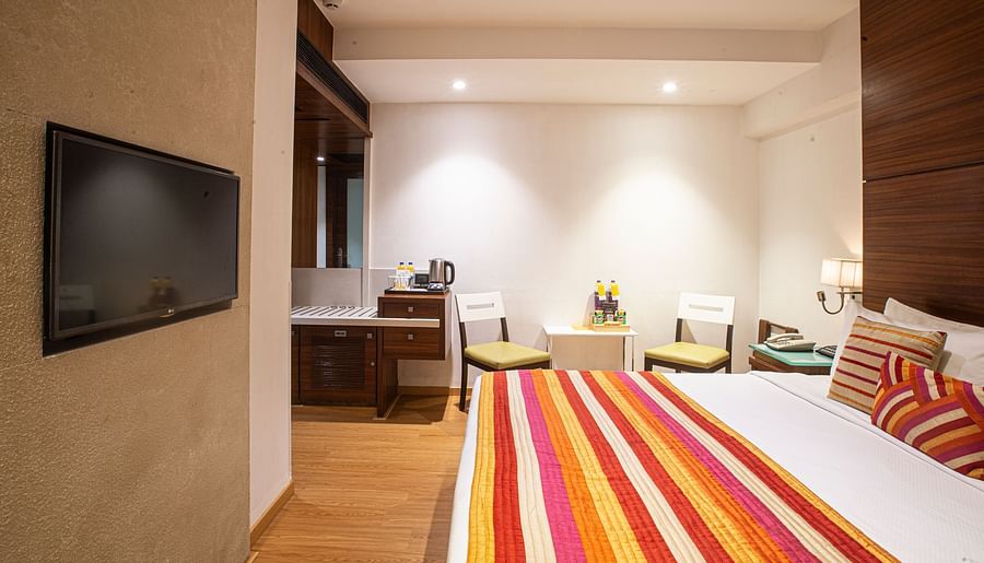 An executive room illuminated by dim lights, featuring a flat-screen TV and a comfy bed, creating a cozy and relaxing atmosphere