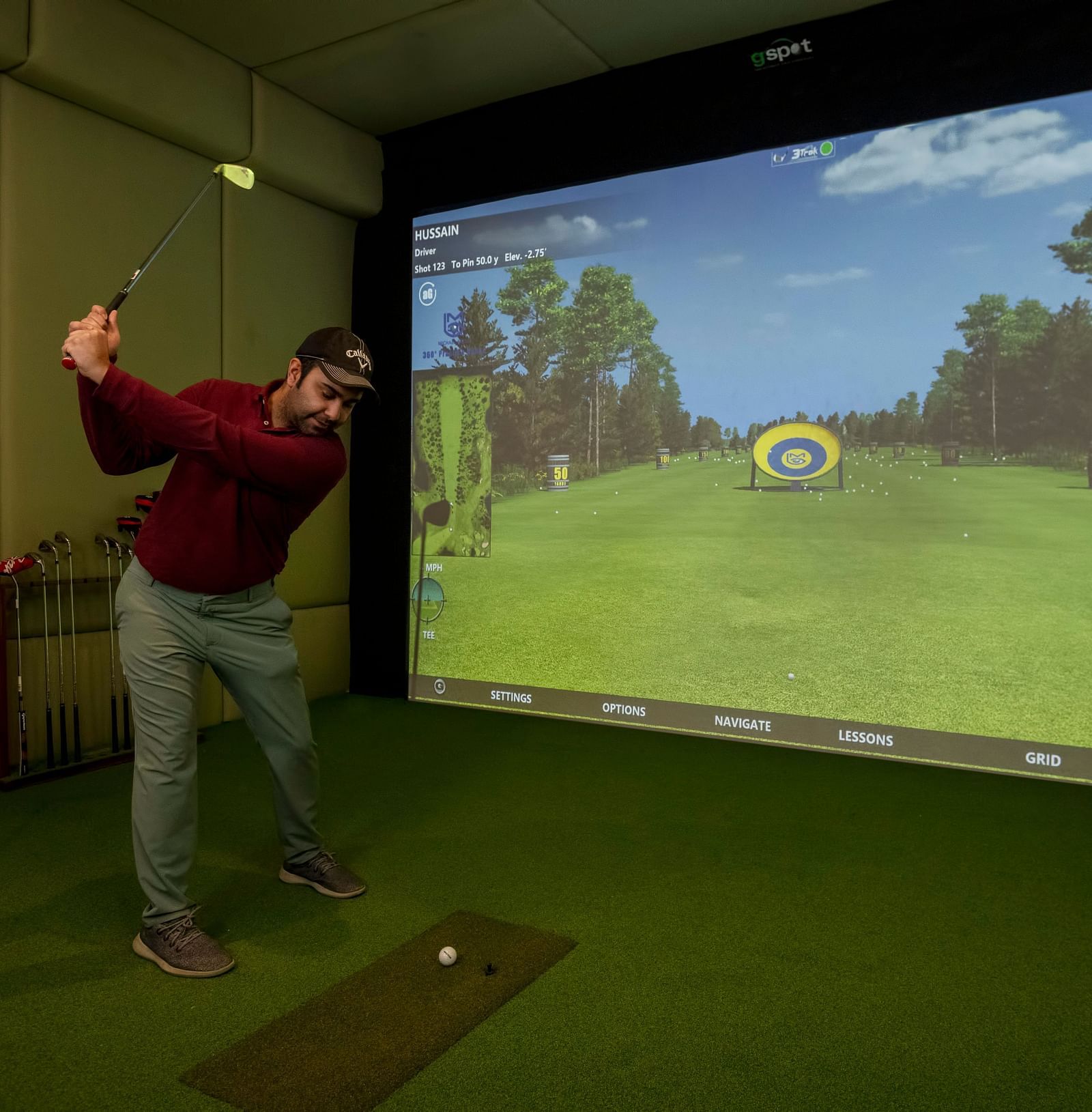 image of a man playing golf in golf simulator at The Claridges New Delhi