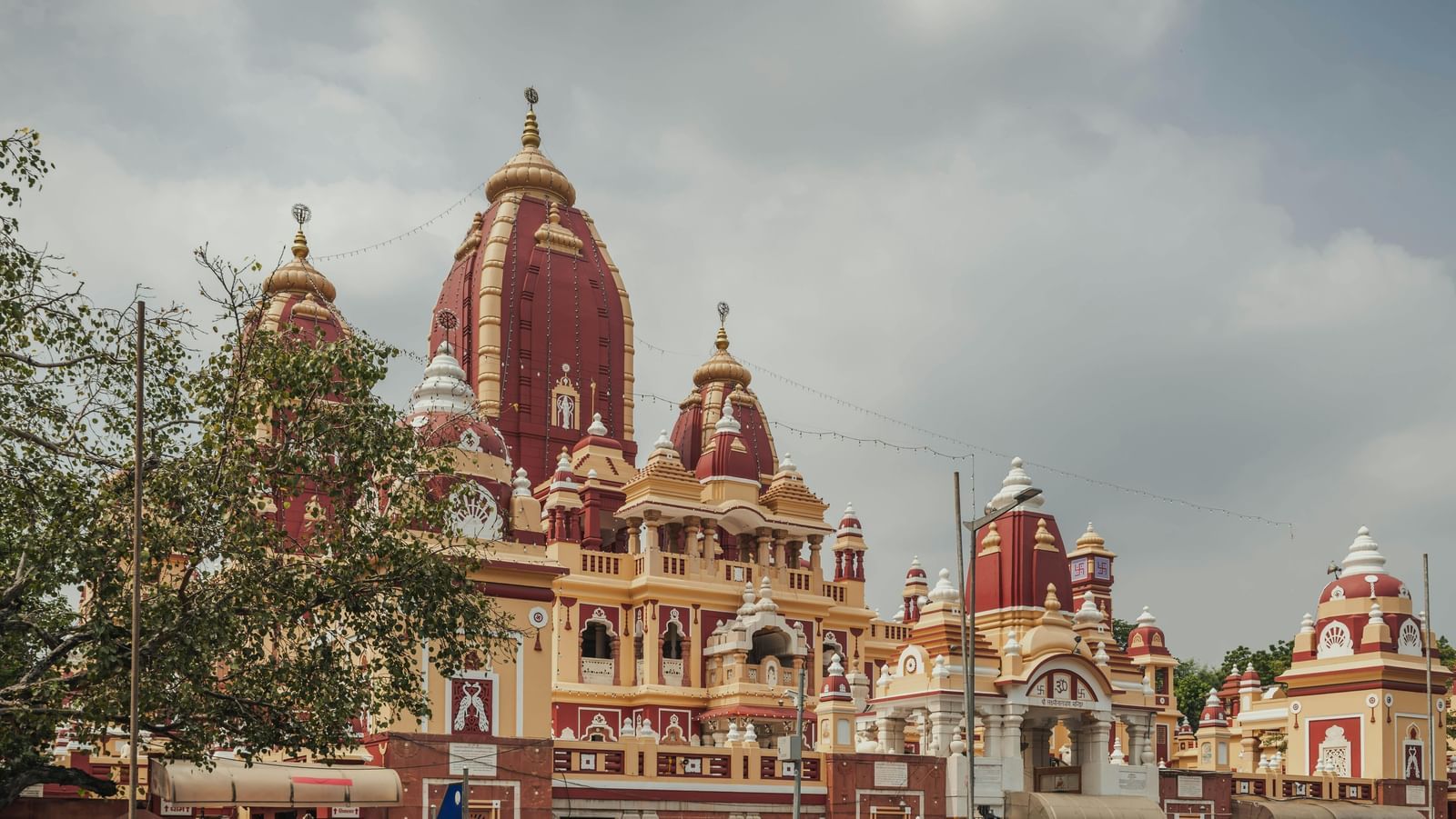 The Temple with red and cream where the temple stands against a cloudy sky with a street in front.