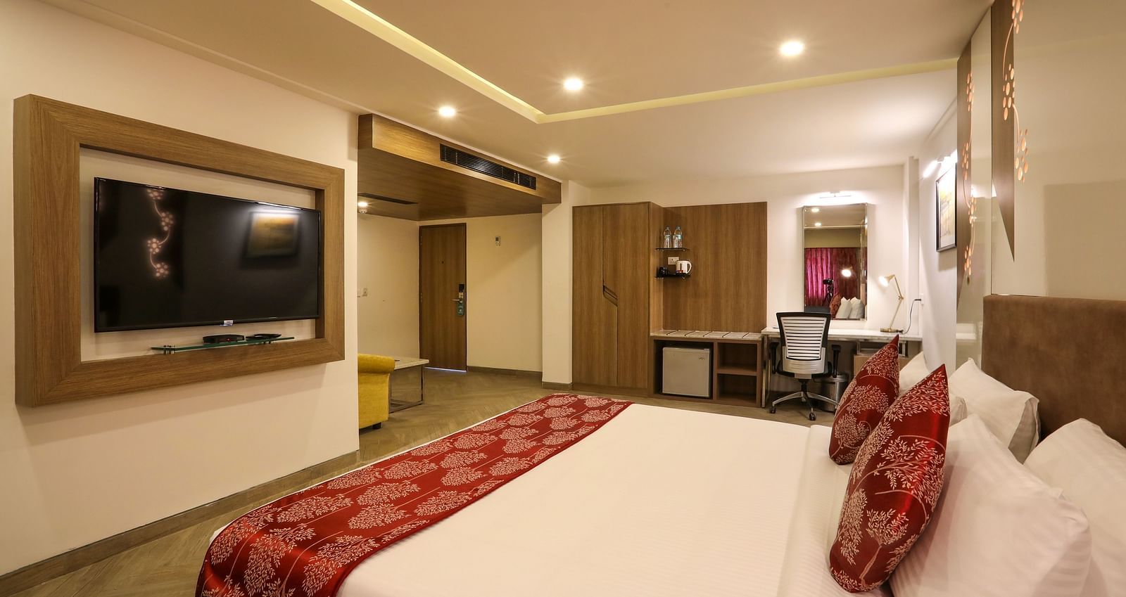 A large bedroom with a mounted television and a workdesk on the other end of the room - Mango Hill Central, Chennai