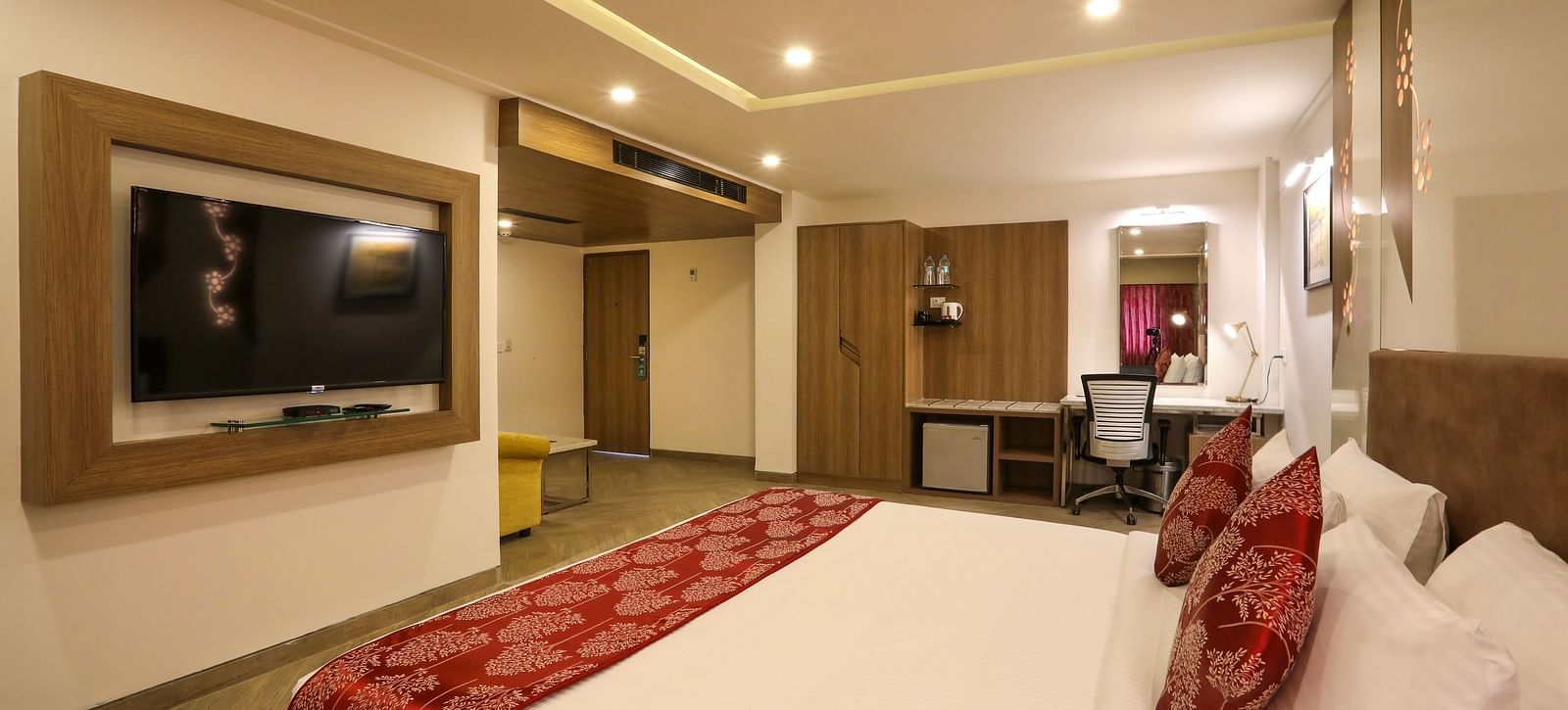 A large bedroom with a mounted television and a workdesk on the other end of the room - Mango Hill Central, Chennai