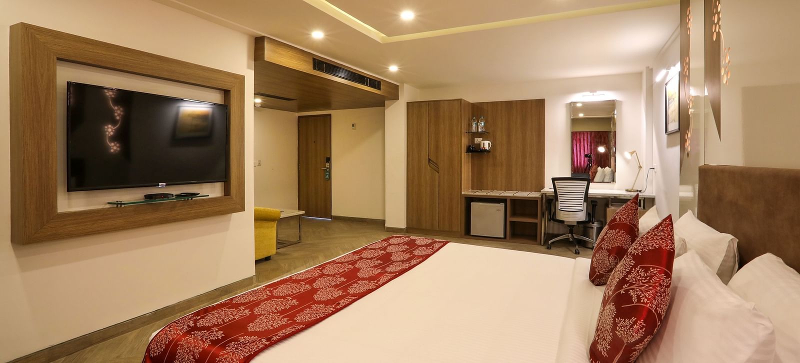A large bedroom with a mounted television and a workdesk on the other end of the room - Mango Hill Central, Chennai