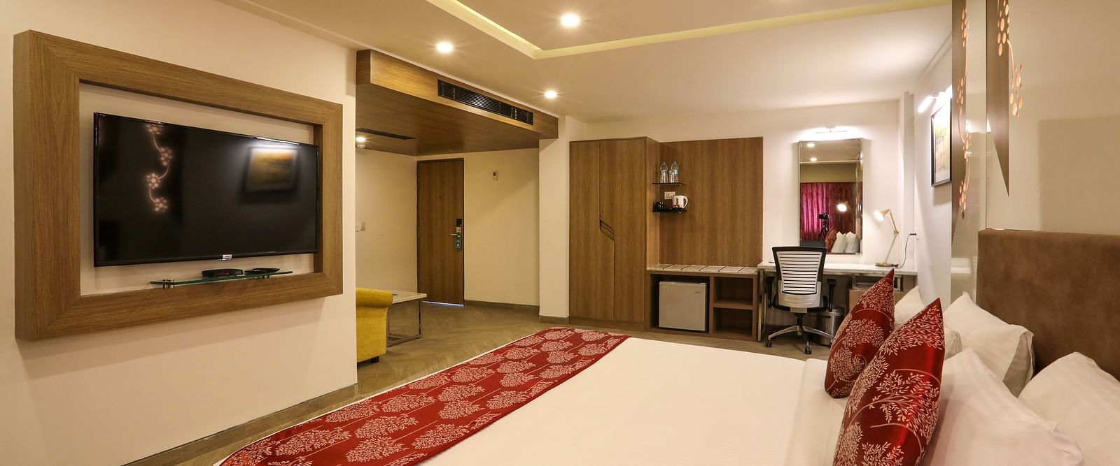 A large bedroom with a mounted television and a workdesk on the other end of the room - Mango Hill Central, Chennai
