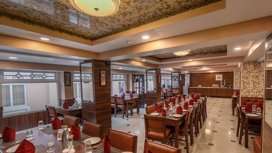 Multiple dining tables and chairs placed in a closed hall that has glass windows | Summit Oakden Resort & Spa, Mall Road