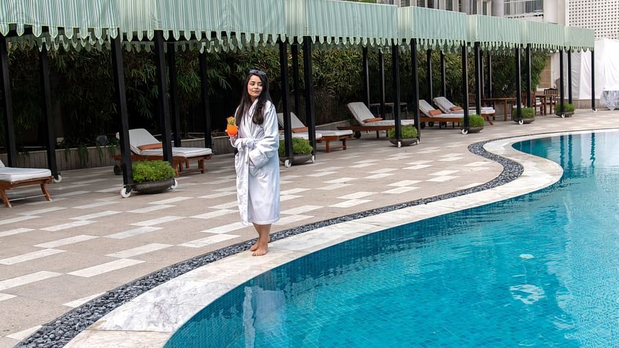 A woman walking beside the pool with a drink in her hand - Claridges Collection