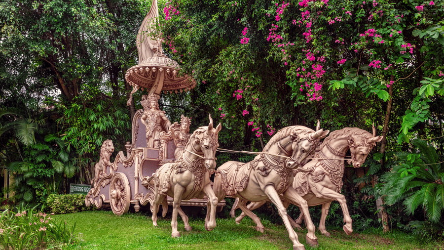 Ornate horse chariot sculpture amidst flowering garden at Mayfair Lagoon, Bhubaneswar