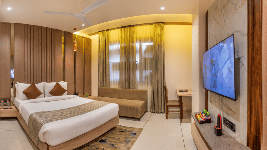 Stylish room at Lords Inn Sangam, Bhopal with two beds, patterned rug, wooden wall panels, and a wall-mounted television.
