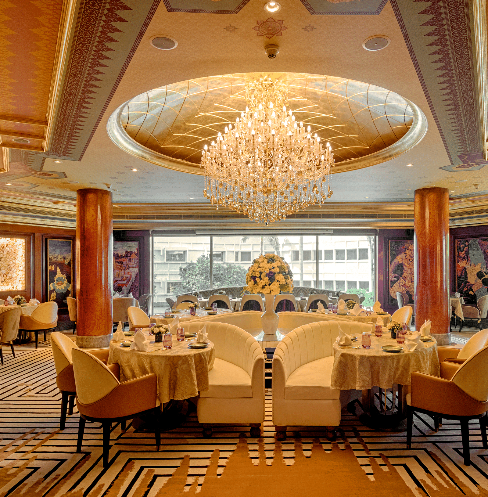 Image of a dining space with chairs and tables with a chandelier on the top at The Claridges New Delhi - Claridges Collection