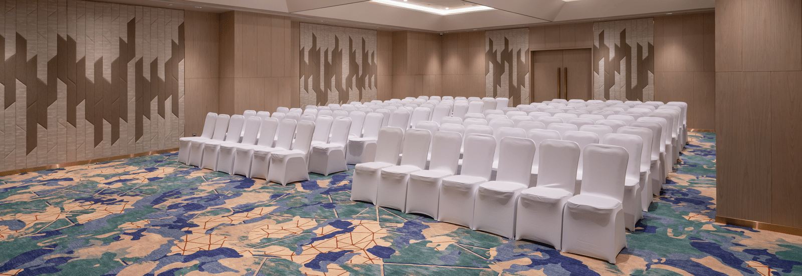 Diagonal view of a meeting room set in theatre style with contemporary lighting at Merlis Hotel, Coimbatore.