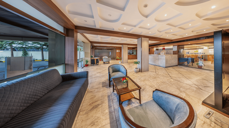 A hotel lobby area of Lords Eco Inn with modern, curved sofas and a wooden ceiling design