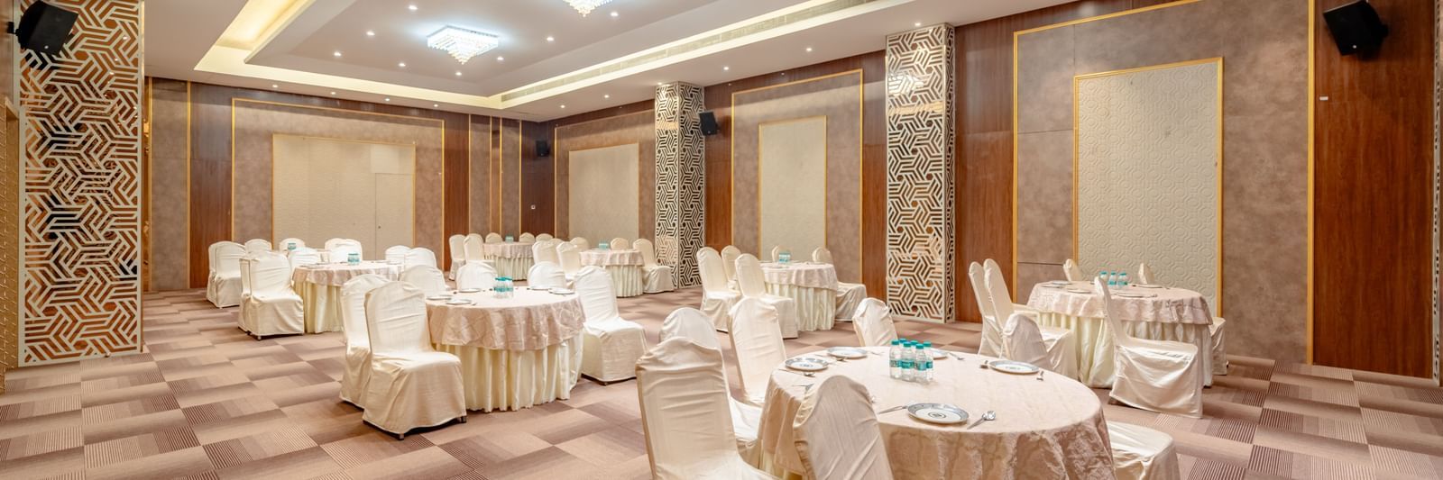 Spacious banquet hall with round tables and elegant chairs | Meetings & Events | Pravasa Hotel, Vijayapura