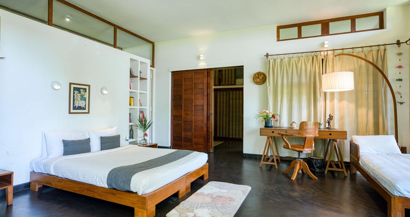 Elegant bedroom with a king-size bed, a study table and chair, complete with elegant lights accentuating  the contemporary vibe of the room.