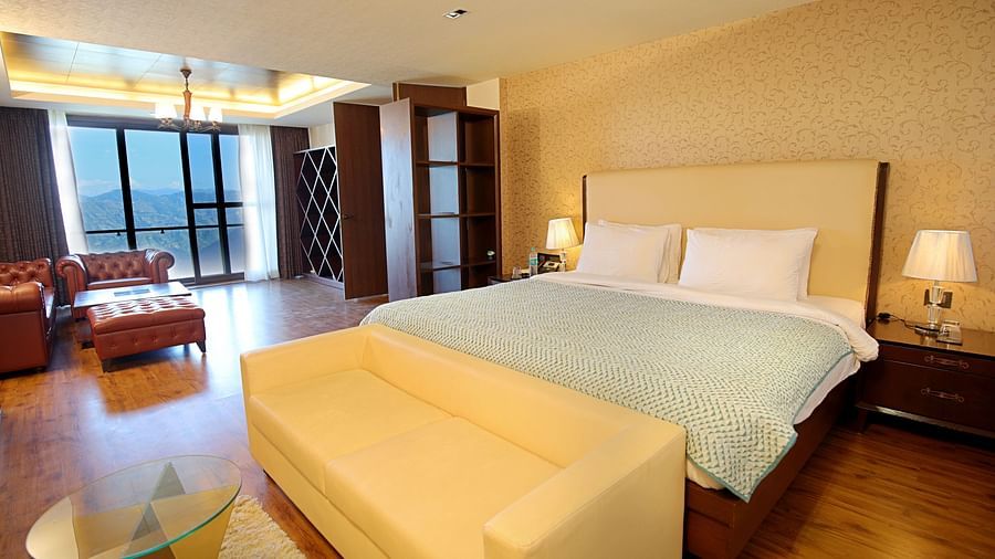 A spacious room featuring a neatly made bed, elegant interiors, and a scenic mountain view visible through the window