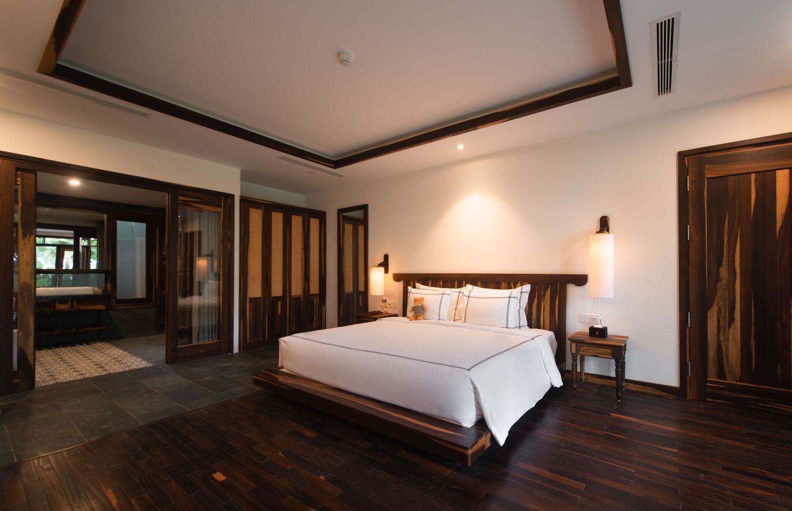 A well-furnished master suite bedroom with a king bed, side lamps and tables  - Alibu Resort Nha Thrang