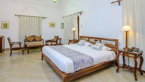 A modern hotel room with a large bed, a seating area with cushioned chairs and a side table - Deo Bagh - 17th Century, Gwalior