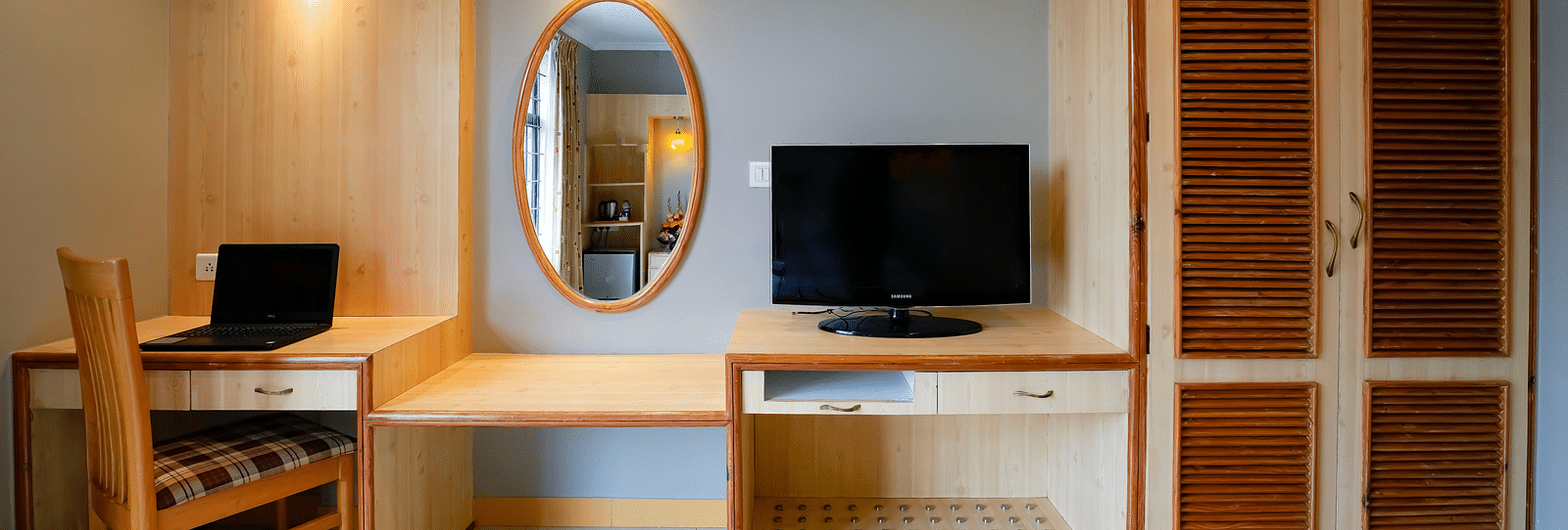 A work space area in our Suite with a laptop and a monitor placed on the desk - Cross Roads Inn, Bengaluru