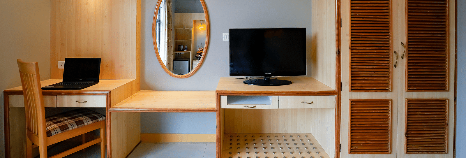 A work space area in our Suite with a laptop and a monitor placed on the desk - Cross Roads Inn, Bengaluru