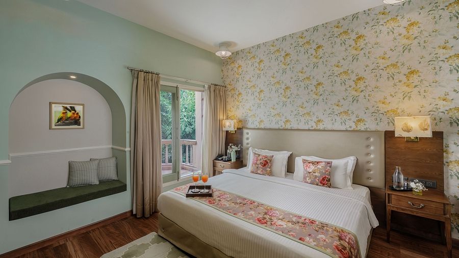 A bedroom at Karma Chalets with a double bed, floral wallpaper, a seating area, and wooden furniture.