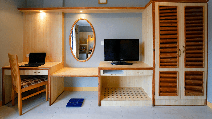 A work space area in our Suite with a laptop and a monitor placed on the desk - Cross Roads Inn, Bengaluru