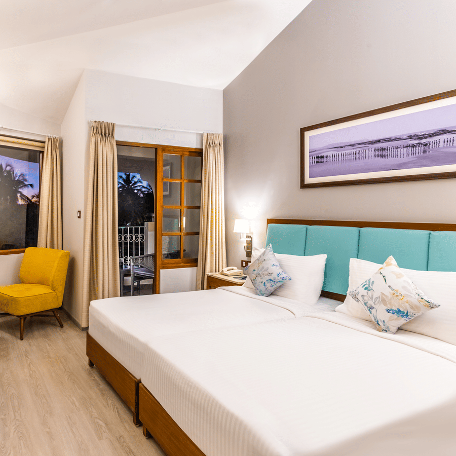 Superior room with double bed, chair, table, tv and a framed art at Heritage Village Resorts & Spa, Goa.