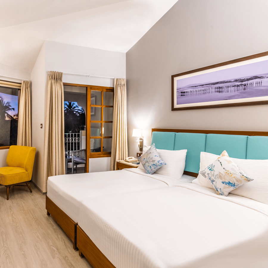 Superior room with double bed, chair, table, tv and a framed art at Heritage Village Resorts & Spa, Goa.