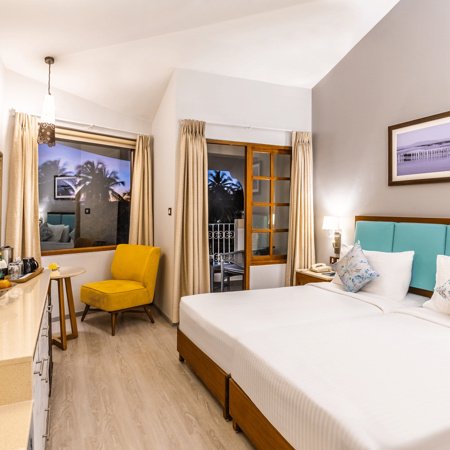 Superior room with double bed, chair, table, tv and a framed art at Heritage Village Resorts & Spa, Goa.