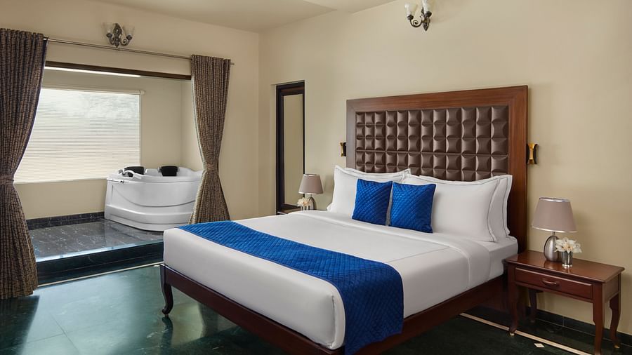 Signature Suite with a large bed, a wooden headboard, and a jacuzzi in an alcove at DGV Resort by Treat, Silvassa.