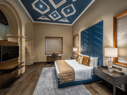 A side view of the bedroom in the Presidential Suite with a large bed, side tables and lamps at Kenilworth Hotel, Kolkata.